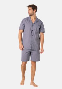Ensemble de pyjama à manches courtes en bleu marine avec des pois blancs. Chemise à boutons et shorts assortis en tissu léger. Pas de motifs ou accents visibles.