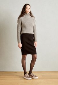 Maglione grigio a coste con colletto a lupetto, gonna a tubino nera, collant trasparenti e sneakers marrone chiaro, con lacci e una texture di tessuto liscia.