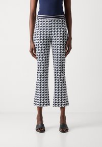 Marineblauwe cropped pants met een aansluitende taille en uitlopende zoom, met een geometrisch ontwerp in het wit en een gladde, zachte textuur.