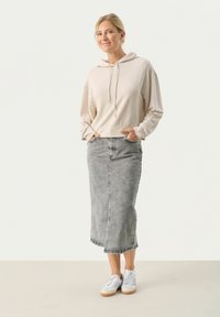 Felpa cropped beige con cordini, abbinata a una gonna midi in denim grigio e sneakers bianche. Presenta tasche frontali e una silhouette dritta.
