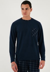 Mornarska majica dugih rukava s kontrastnom karirastom džepom. Mekana tekstura, okrugli izrez, nosi se s kariranim donjim dijelom pidžame.