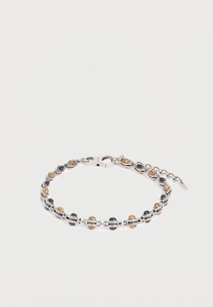 Silbernes Armband mit abwechselnd kleinen schwarzen und bernsteinfarbenen runden Steinen, verbunden durch dünne Metallstäbe und einem Verschluss mit verstellbarer Kette.