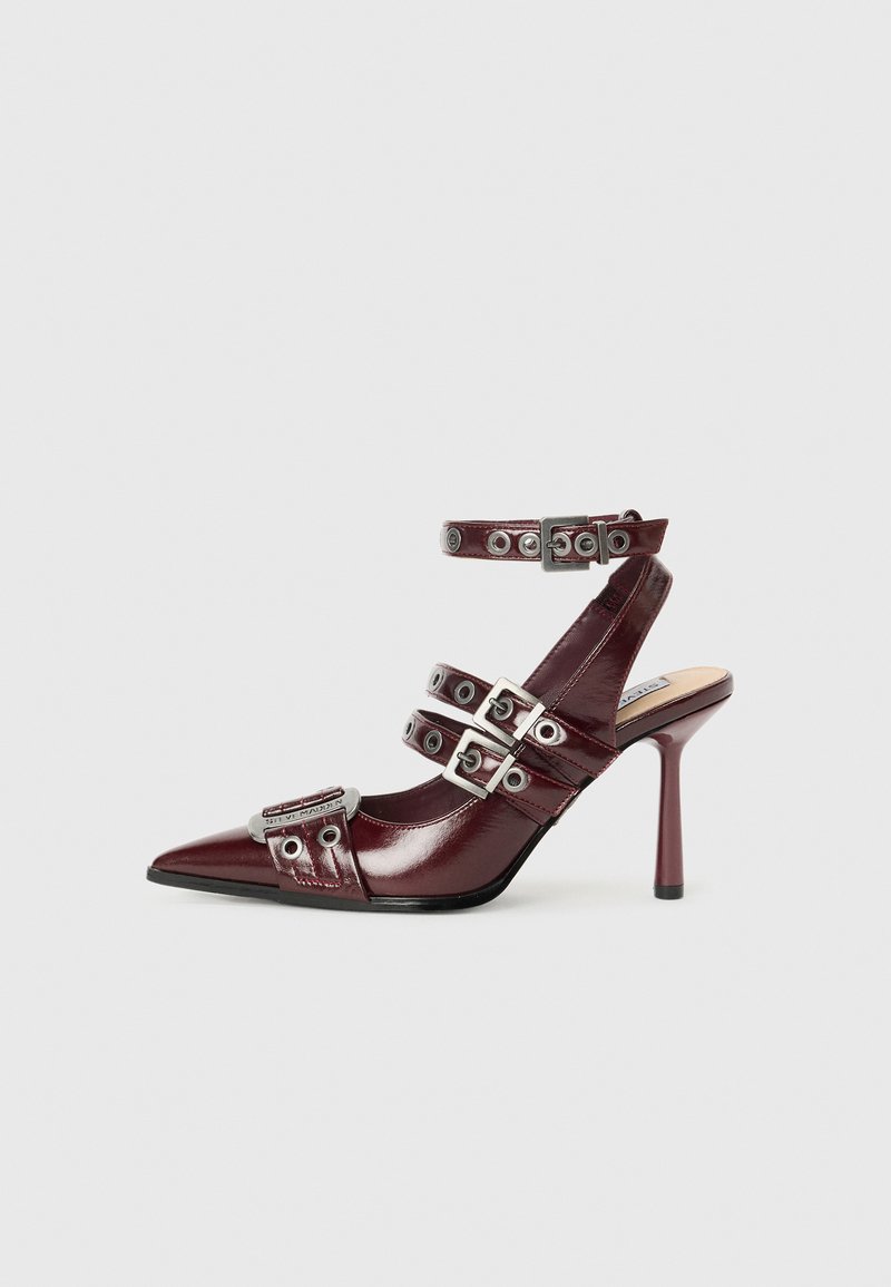Burgundy patent leather high-heeled sandal with pointed toe, silver buckle accents, and ankle straps. Sleek design with glossy texture.