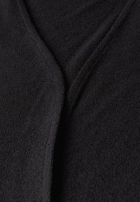 Indumento nero a collo a V realizzato in tessuto morbido e testurizzato con una finitura liscia; presenta un design pulito e minimalista senza hardware visibile.
