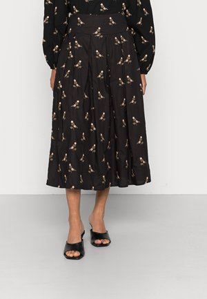 Zwarte geplooide midi-rok met een kleine roze bloemprint, gedragen met een bijpassende blouse met lange mouwen en zwarte sandalen met open teen en hak.