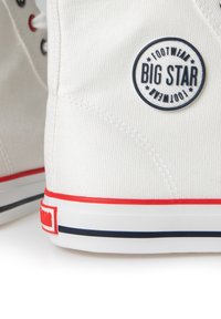 White canvas sneakers with red and navy accents. Features a round blue logo that reads "BIG STAR FOOTWEAR" on the outer side.
