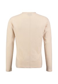 Camicia a maniche lunghe beige, realizzata in tessuto morbido, presenta un colletto tondo e una cucitura centrale che corre lungo la schiena. Design minimalista.