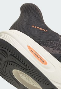 Čierna športová obuv s priedušným sieťovaným zvrškom, bielou strednou podrážkou a textúrovanou čiernou vonkajšou podrážkou. Obsahuje akcenty značiek "CLOUDfoam" a "RAPIDFIT".