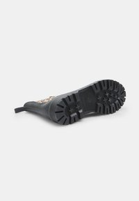 Cizma din cauciuc neagră cu o talpă texturată, având un design cu imprimeu de leopard pe partea superioară. Material din cauciuc, bot rotund și un hașur pentru tragere în spate.
