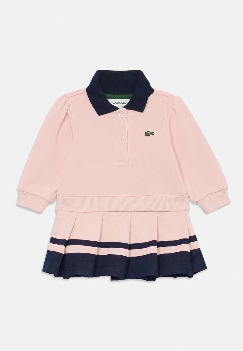 Ροζ μακρυμάνικο φόρεμα πόλο με ναυτική κολαρίνο και πλισέ φούστα με δύο ναυτικές ρίγες και ένα μικρό πράσινο λογότυπο κροκοδείλου.