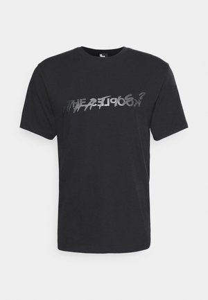 Black cotton t-shirt with short sleeves, featuring a distorted, reflective text print in silver across the chest. Casual fit.