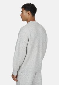 Szary sweter z dzianiny z okrągłym dekoltem, prążkowanymi mankietami i dołem oraz teksturowanym wykończeniem. Stylizowany w luźnym kroju.