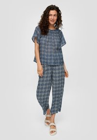 Marineblauw patroon top met vloeiende mouwen, gecombineerd met bijpassende broek. De stof lijkt lichtgewicht met een soepele textuur.