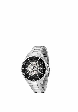 Orologio da polso in metallo argentato con ghiera nera, quadrante scheletro trasparente che mostra la meccanica interna e bracciale metallico a maglie.