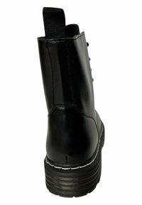Botín de cuero negro hasta el tobillo con puntera redondeada, suela texturizada y detalle de costura blanca. Diseñado con una lengüeta en la parte trasera y ojales para los cordones.