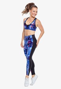 Blauwe en zwarte sportkleding met een geometrisch patroon. De top is een sportbh; de legging bevat levendige ontwerpelementen.