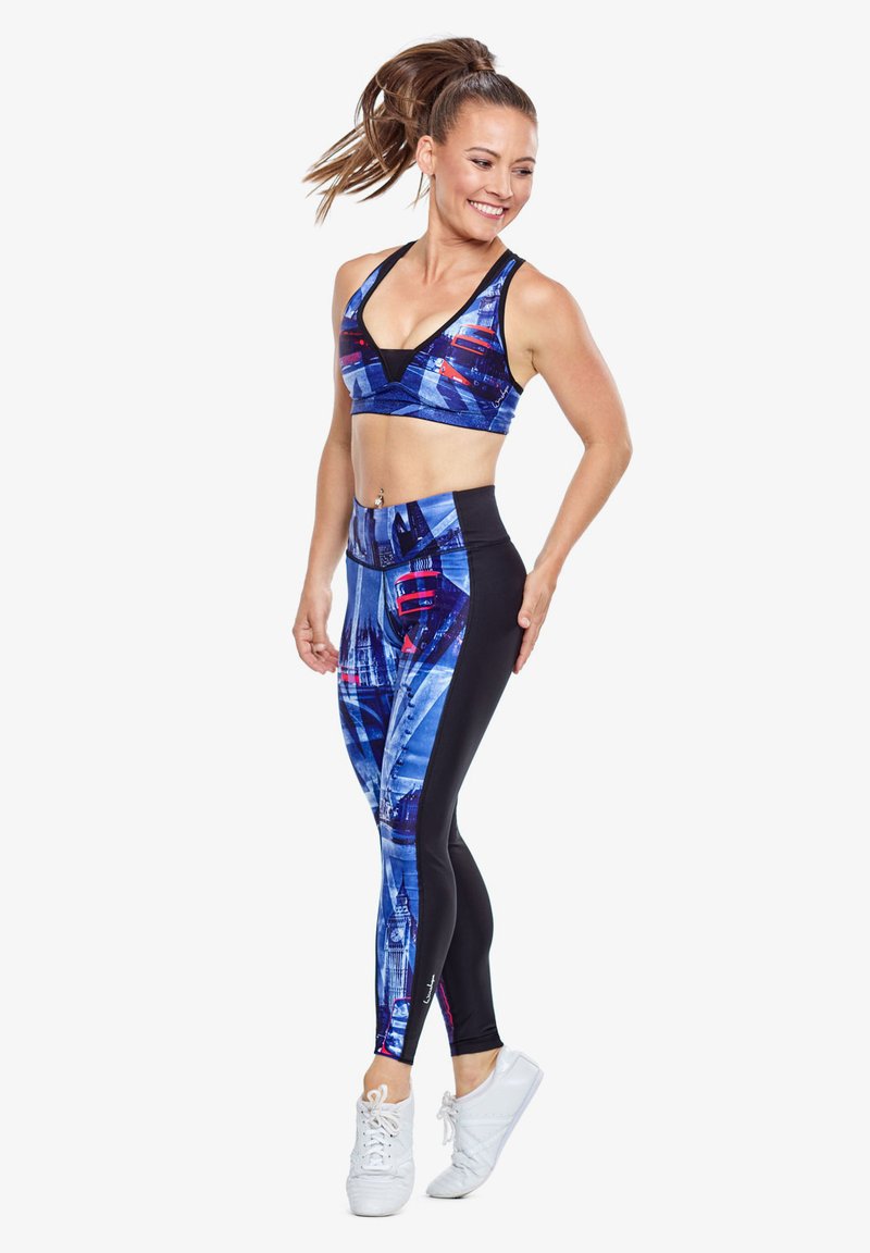 Blauwe en zwarte sportkleding met een geometrisch patroon. De top is een sportbh; de legging bevat levendige ontwerpelementen.