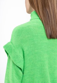 Pulover verde tricotat cu guler înalt, având un model texturat și mâneci răsucite. Materialul pare moale și respirabil.