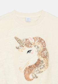 Σουέτερ από φλις σε κρέμα χρώμα, με σχέδιο μονόκερου από παγιέτες σε χρυσό, ροζ χρυσό και ασημί λεπτομέρειες, με κεντημένο πρόσωπο και ροζ λεπτομέρειες.