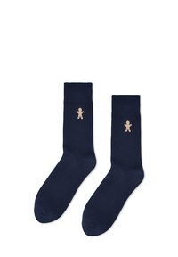 Granatowe bawełniane skarpetki z prążkowanymi ściągaczami i jasnobrązowym pierniczkiem wyszytym na zewnętrznej stronie. Gładka faktura, standardowa długość do wysokości łydki.