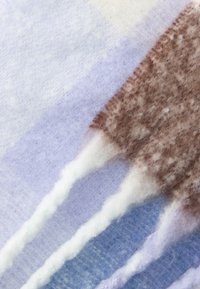 Vilnas šalle ar patchwork dizainu gaiši violetās, zilās un brūnās krāsās; maiga tekstūra ar frēzojumiem malās.