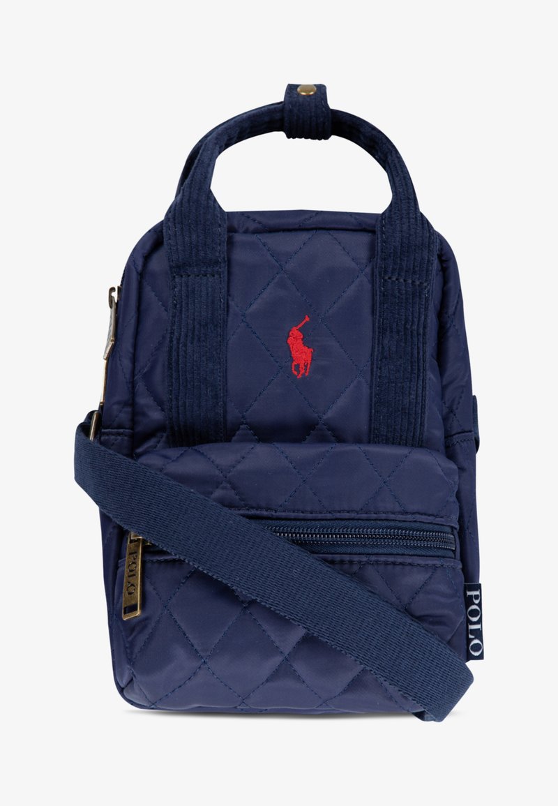 Navy quilted backpack with tonal stitching, red embroidered logo, dual handles, and a removable strap. Features a front zip pocket.