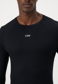 Camisa preta justa de manga longa, feita de material suave, com decote arredondado e logótipo branco "ICIW" centrado no peito.