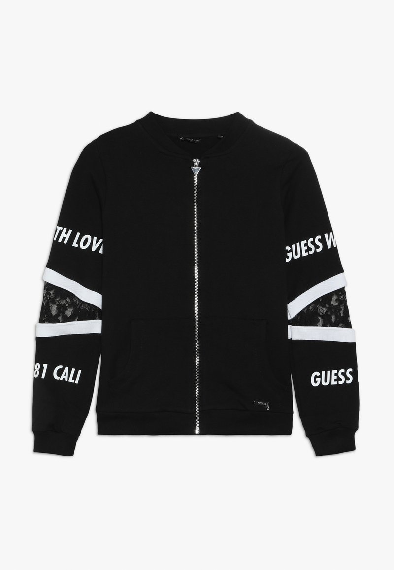 Veste noire zippée avec texte blanc sur les manches, inserts en dentelle sous les rayures blanches, et deux poches avant.