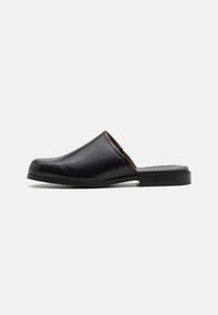 Černá kožená slip-on bota s kulatou špičkou, hladkým povrchem, minimalistickým designem a nízkým obdélníkovým podpatkem. Vhodná na volný čas.