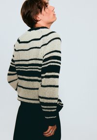 Maglione a righe in crema e nero; presenta una vestibilità rilassata, un materiale testurizzato e colletto e polsini a coste.
