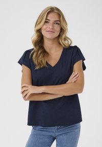 Camiseta de cuello en V azul marino con mangas cortas. Presenta detalles de encaje en los hombros, fabricada con un material suave y ligero. Ajuste casual.