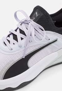 Light purple athletic shoe with textured black accents. Features flat laces, a flexible sole, and a prominent black logo on the side.