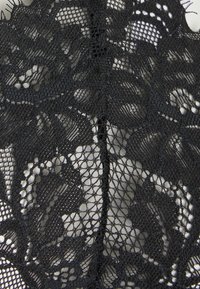 Tissu en dentelle noire avec des motifs florauxintriqués, une texture en maille fine et une transparence variable. Le design est symétrique et détaillé.