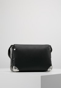 Sort læderhåndtaske med rektangulært form, sølvfarvede hardware-accents i hjørnerne og en kædestrop til bæring.