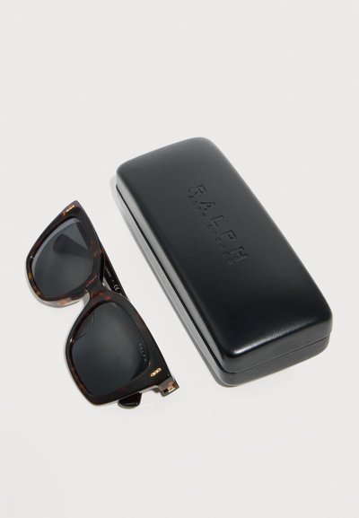 Γυαλιά ηλίου oversized σε σχέδιο χελώνας με σκούρους φακούς δίπλα σε μαύρη σκληρή θήκη με το λογότυπο Ralph Lauren πάνω σε λευκή επιφάνεια.
