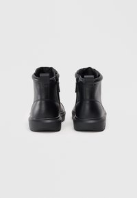 Botines negros de tobillo hechos de cuero texturizado con un acabado suave y mate. Cuentan con un cierre de cremallera en la parte trasera y una suela de goma duradera.