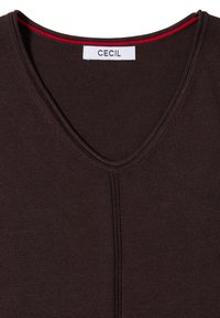 Chemise marron foncé à col en V avec une couture centrale visible et une étiquette blanche avec le texte "CECIL" à l'intérieur du col.