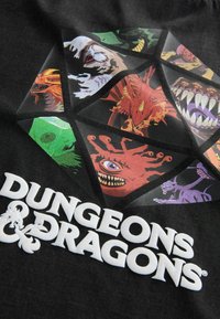 Schwarzes T-Shirt mit einem mehrfarbigen Dungeons & Dragons Grafikdesign, das verschiedene Monsterillustrationen und fettgedruckten weißen Text darunter zeigt.