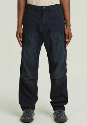 Pantaloni cargo neri con molte tasche, vestibilità ampia, realizzati in materiale resistente. Caratterizzati da chiusura con bottone e cuciture rinforzate.
