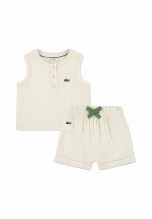 Haut bébé sans manches en côte crème avec boutons et shorts assortis avec nœud vert et logos crocodile Lacoste sur les deux pièces.