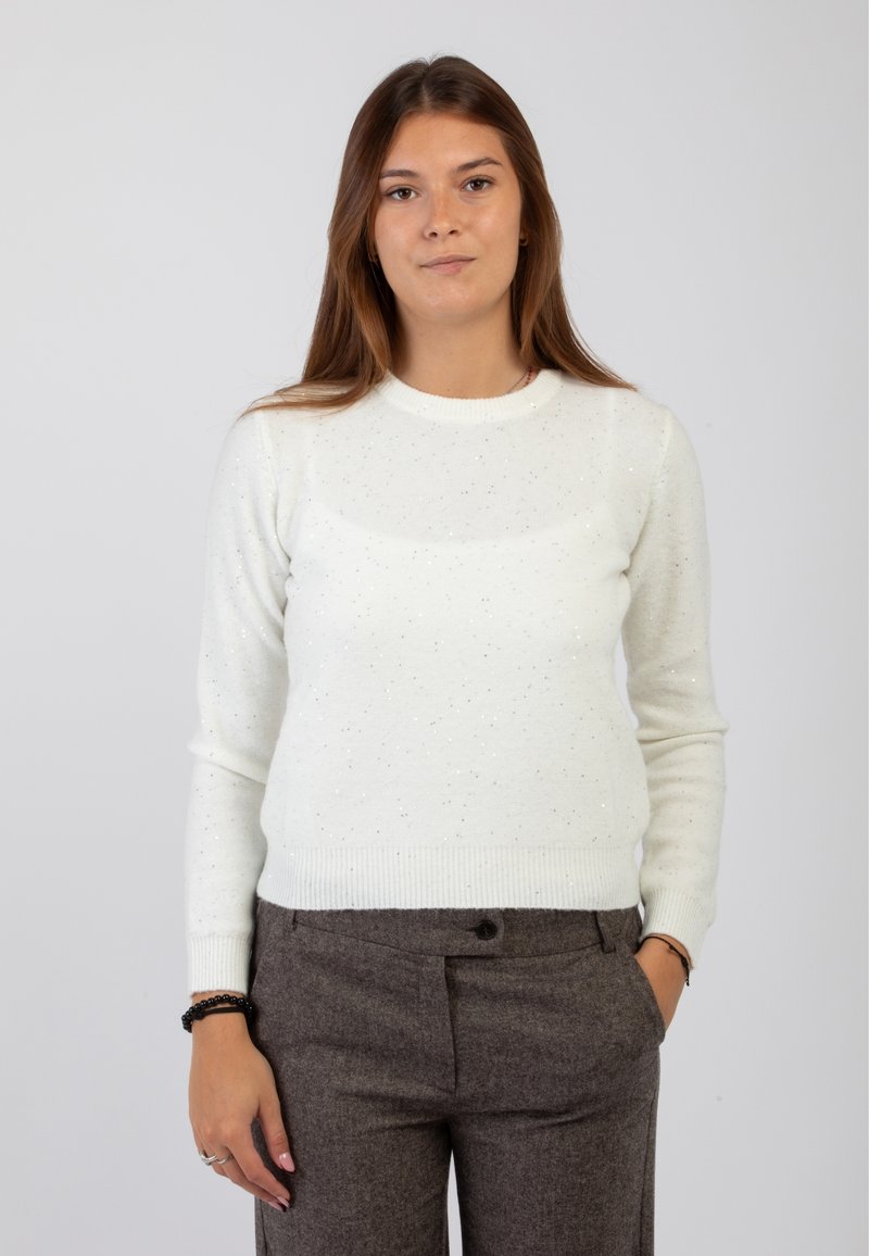 Maglione a maglia color crema con dettagli scintillanti, scollo rotondo e polsini a coste, abbinato a pantaloni scuri grigi su misura.
