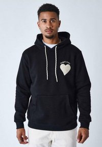 Sudadera negra con cordones blancos, bolsillo frontal y diseño de corazón bordado. Hecha de una tela suave con un ajuste relajado.