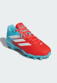 Crvene i plave kopačke s bijelim prugama, s modeliranim kopačkama i crvenim vezicama, namijenjene za sportske aktivnosti na otvorenom na travi ili umjetnoj podlozi.