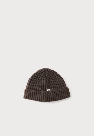 Bonnet en tricot côtelé marron foncé avec un revers et une petite étiquette blanche à l'avant sur un fond uni.