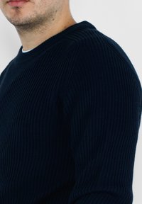 Maglione a coste navy con scollo rotondo e maniche lunghe, caratterizzato da un motivo testurizzato e un tessuto morbido.