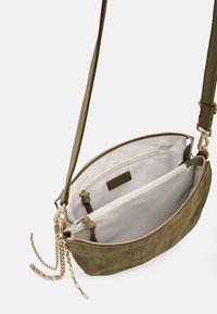 Borsa a tracolla in pelle verde oliva con superficie testurizzata, doppio scomparto, fodera in tessuto crema, dettagli dorati e tracolla regolabile.