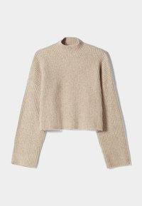 Beige västityylinen ribbineuloksesta valmistettu neule, jossa on korkea kaulus ja pitkät hihat hieman väljässä istuvuudessa. Pinnan tekstuuri yksityiskohtana.