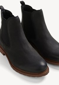 Schwarze Leder Chelsea-Stiefel mit elastischen Seitenpanels und strukturierter Oberfläche, ausgestattet mit einer braunen Gummisohle. Geeignet für die Freizeit.