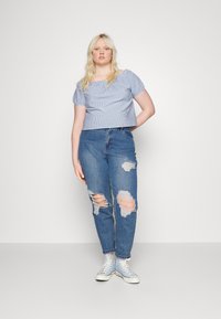 Top cropped azul e branco com riscas, mangas curtas bufantes, combinado com jeans rasgados azul claro e ténis brancos de cano alto.