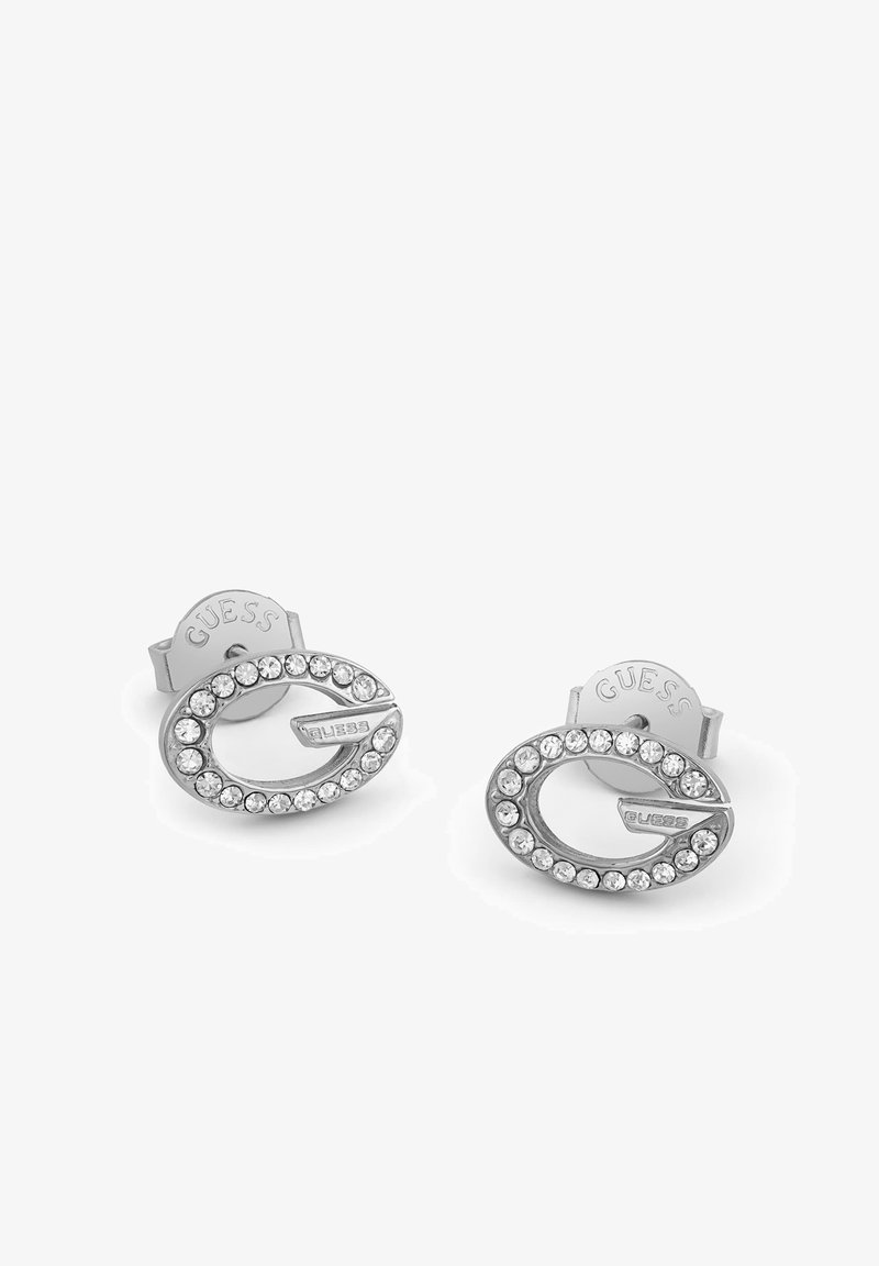 Boucles d'oreilles clous en argent en forme de la lettre G, bordées de strass clairs et avec le logo Guess sur chaque pièce.